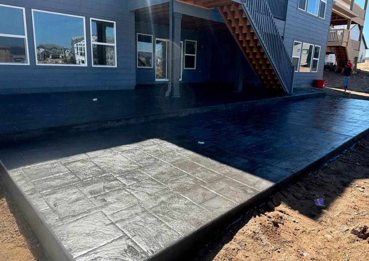 Stamped concrete patio beside a blue house in low evening light